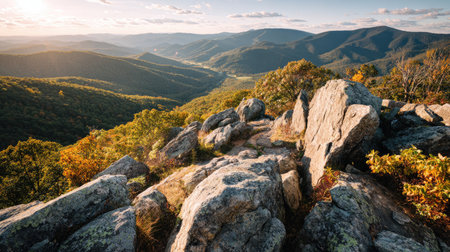 Experience a breathtaking view of rugged rocks and vibrant autumn foliage, offering a stunning sunset over the valley and distant mountains in a serene natural setting.の素材