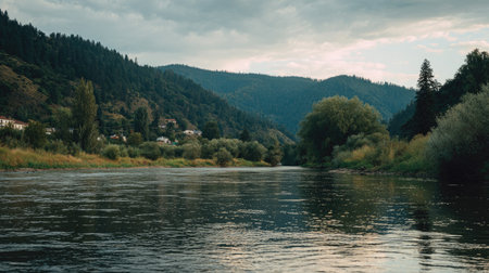 A breathtaking view of a calm river meandering through verdant forests and rolling hills, framed by dramatic clouds in the sky, perfect for nature enthusiasts.の素材