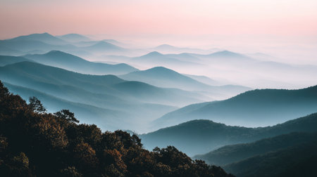 A stunning view of layered mountains at dawn, enveloped in soft mist with a harmonious blend of blue and purple tones, offering a peaceful escape into nature's beauty.の素材