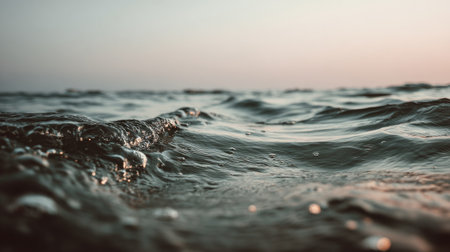 A serene view of gentle ocean waves at sunset, capturing the tranquil beauty of nature with soft light reflecting on the water surface for meditation or relaxation.の素材