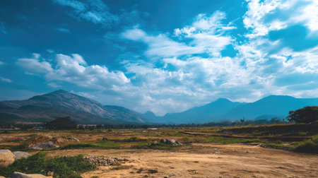 A stunning landscape showcasing majestic mountains under a bright blue sky filled with fluffy clouds, ideal for nature enthusiasts and travelers seeking serenity.の素材