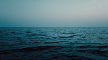 This tranquil ocean scene captures calm waters at dusk, showcasing soft blue tones and a minimalist landscape that evokes feelings of peace and relaxation.の素材