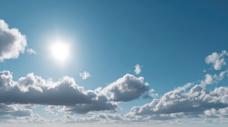 A bright blue sky filled with fluffy white clouds and a warm sun radiating light, creating a serene atmosphere perfect for relaxation and outdoor enjoyment.の素材