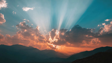 A stunning sunset unfolds over distant mountains, featuring dramatic clouds and radiant rays that illuminate the sky. This serene landscape captures the beauty of nature.の素材