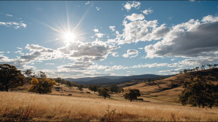 A breathtaking view of a peaceful landscape featuring gentle rolling hills under a blue sky, adorned with fluffy clouds and radiant sunlight. Ideal for nature lovers.の素材