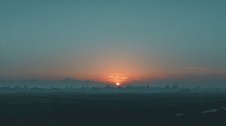 A beautiful sunrise paints the sky in soft colors over a misty landscape, with silhouetted trees creating a tranquil scene perfect for nature lovers and photographers.の素材