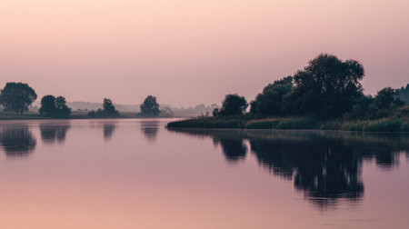 A serene view of a calm river at dawn, featuring gentle pastel skies and clear reflections of trees along the riverbank, perfect for evoking tranquility.の素材