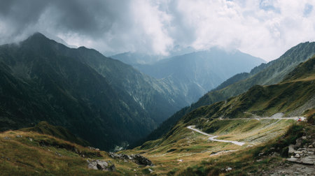 A stunning view of a mountain landscape featuring dramatic clouds overhead. The lush green hills and winding path invite exploration and adventure in nature's beauty.の素材