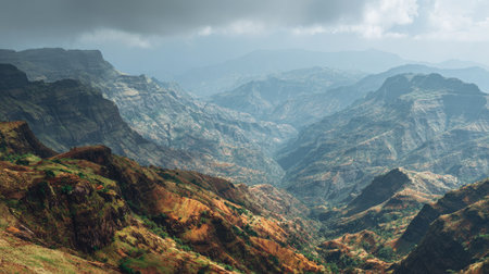 Experience the stunning beauty of a mountain range, where rugged terrain meets lush greenery under a dramatic cloudy sky. A perfect nature landscape for adventure seekers.の素材