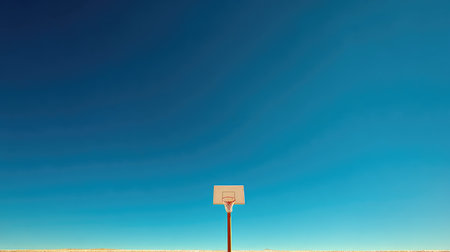 A striking image of a lone basketball hoop set against a bright blue sky. The scene captures the essence of freedom and solitude, perfect for inspiring a sense of calm.の素材