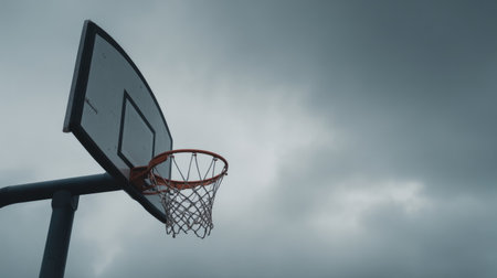 A solitary basketball hoop framed by a moody sky, capturing the essence of sport and outdoor recreation, highlighting the contrast between play and nature.の素材