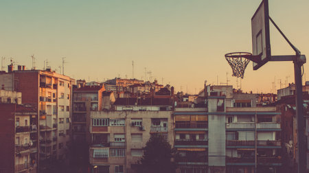 Capturing a serene urban sunset scene, this image features a basketball hoop with a backdrop of residential buildings basking in the warm glow of evening light.の素材
