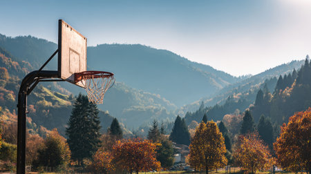A serene scene featuring a basketball hoop set against a backdrop of majestic mountains and colorful autumn trees, perfect for leisure and outdoor activities.の素材