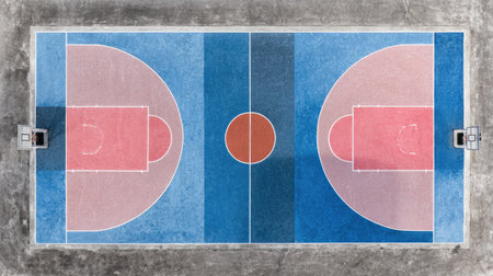 This aerial view showcases a vibrant outdoor basketball court featuring distinct red and blue markings, perfect for sports enthusiasts and recreational activities.の素材