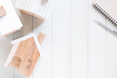 Miniature house model with pencil and notebook on white wood background, copy spaceの写真素材