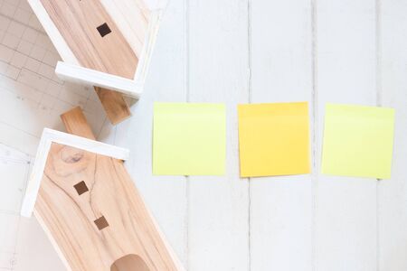 Miniature house model with blueprint plan, blank sticky note on white wood backgroundの写真素材