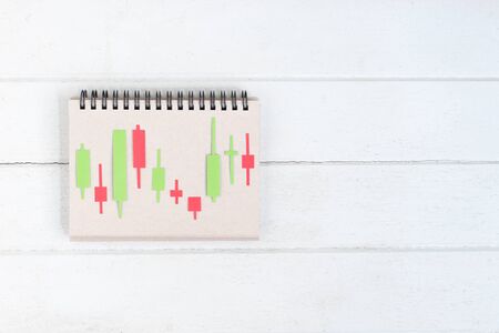 Candlestick chart make from color paper Green and red on paper notebook on white wood background,...