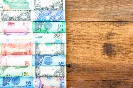 A backgrounds with colorful of many roll curreny from many country put on a brown wood