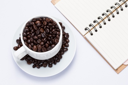 isolate of coffee bean in white cup on the white table with note bookの写真素材