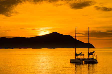 sunset over sea with sailboatの写真素材