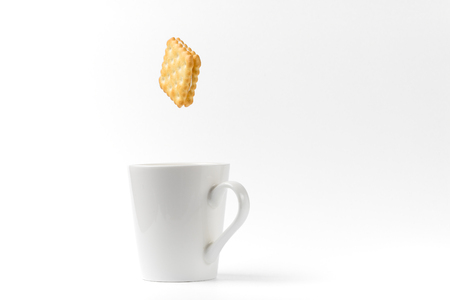 square sandwich cracker falling to coffee cup on white background with some shadowの写真素材
