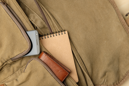 Men's bag stuff top view, navy-green fabric messenger bag have brown leather wallet, smartphone, notebook insideの写真素材