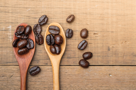 Coffee beans on wood spoon over wooden tableの写真素材