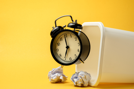 black vintage alarm clock floating on the air from white trash with yellow color backgroundの写真素材