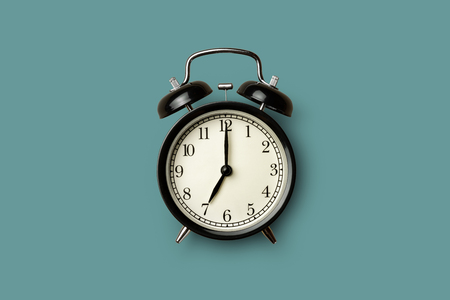 black vintage alarm clock on green color backgroundの写真素材