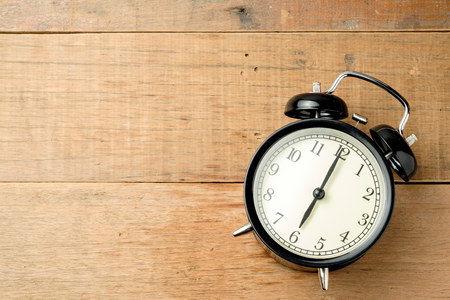 black vintage alarm clock on wooden tableの写真素材