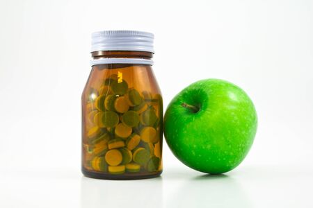Medicine glass bottle with pills and appleの写真素材
