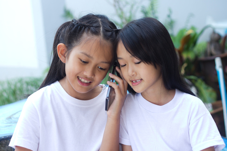 Two asian sister happy with cell phoneの写真素材