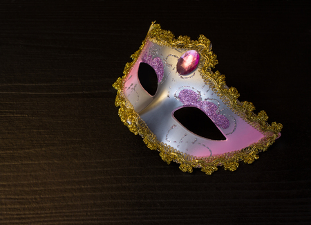 Carnival mask on black wooden background with night lightの写真素材