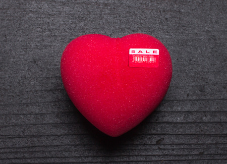 Heart for sale or Love for sale. Red heart shape with sale price tag on black board backgroundの写真素材