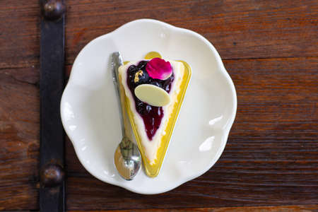 Piece of sponge cake decorate in white plat set on wooden tableの写真素材