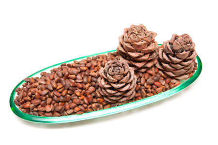 Three pine cones and pine nuts in a glass rook