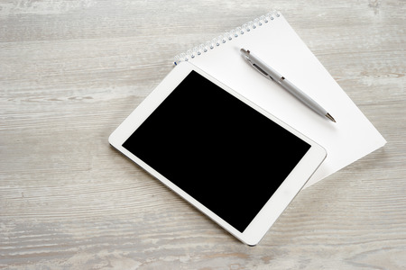 Tablet with notebook on wooden table and penの写真素材