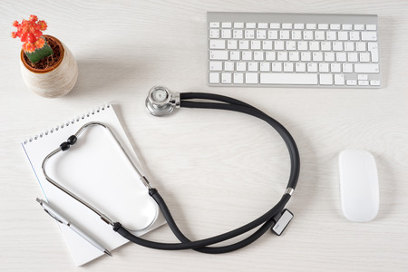 Workplace with notepad and keyboard, and stethoscopeの写真素材