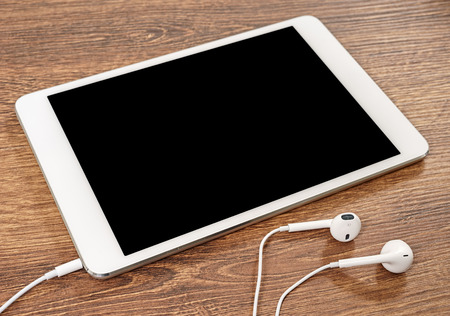 Headphones and tablet computer are on the tableの写真素材