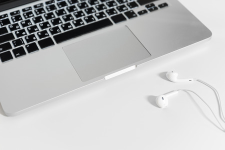 Top view of the keyboard of the laptop on white Desk with headphones