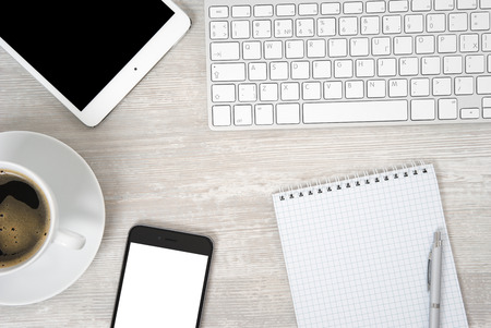 Office table with notebook, computer keyboard and mouse, tablet pc and smartphone