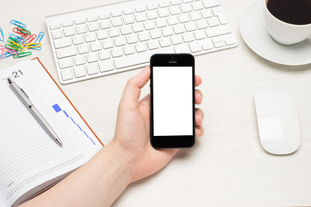 The smartphone in your hand on the table with laptopの写真素材