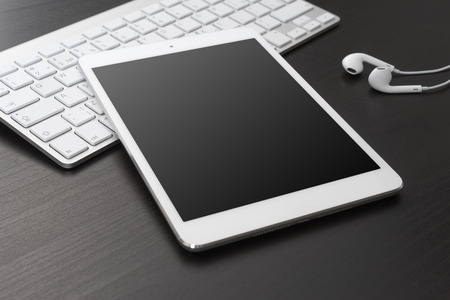 Digital tablet and headphones on a dark table.の写真素材