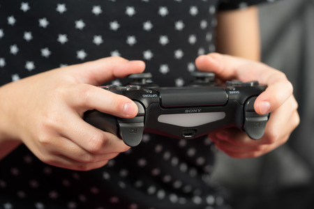 UFA, RUSSIA - NOVEMBER 12, 2017: Hand girl playing Sony Dualshock 4 controller for PlayStation 4 pro. Sony PlayStation 4 pro game console of the eighth generation.のeditorial素材