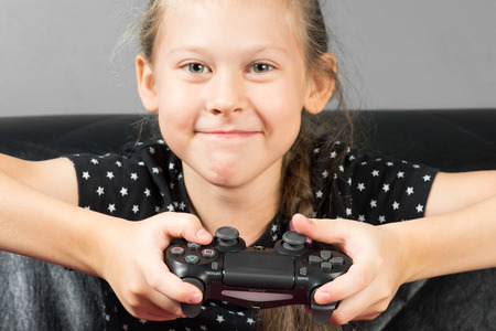 UFA, RUSSIA - NOVEMBER 12, 2017: Hand girl playing Sony Dualshock 4 controller for PlayStation 4 pro. Sony PlayStation 4 pro game console of the eighth generation.のeditorial素材