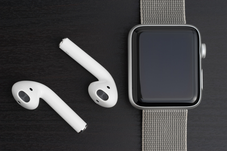 UFA, RUSSIA - OCTOBER 20, 2017: AirPods wireless headphones developed by Apple Inc. AirPods are on the table and apple watch.のeditorial素材