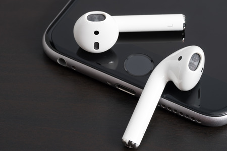 UFA, RUSSIA - OCTOBER 20, 2017: AirPods wireless headphones developed by Apple Inc. AirPods is on the open box and iphone.のeditorial素材
