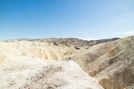 Man overlooking epic view of hot arid dry desert landscape at Zabriskie point, Death Valley National Park, United Statesの写真素材