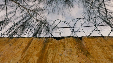 Old Soviet prison in winter, high fence with barbed wire and snow