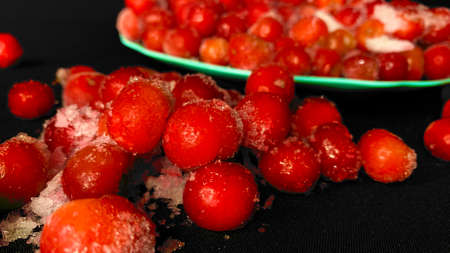 Cold cherry in the winter season. Many ripe red cherries in ice are scattered on the tableの写真素材
